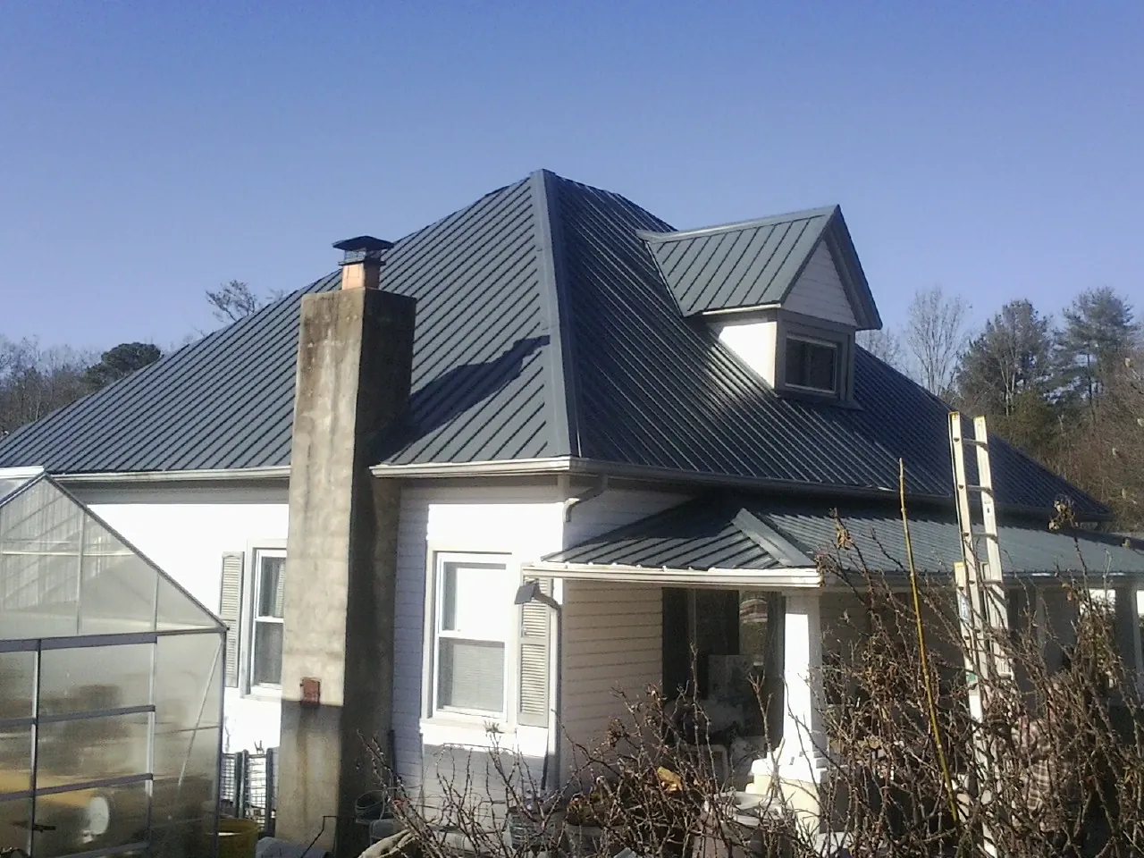 Dark blue standing seam metal roof on a white farmhouse with dormer — Slate & Tile Roof Repair by Roofing Brothers in Saint Paul