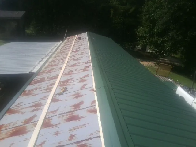 Old rusted panels beside newly installed green metal roofing — Wind Damage Roof Repair by Roofing Brothers in Saint Paul