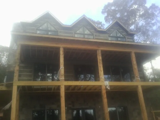 Dormers and porch framing on a large log home under construction — Roof Coating work by our crew in Saint Paul