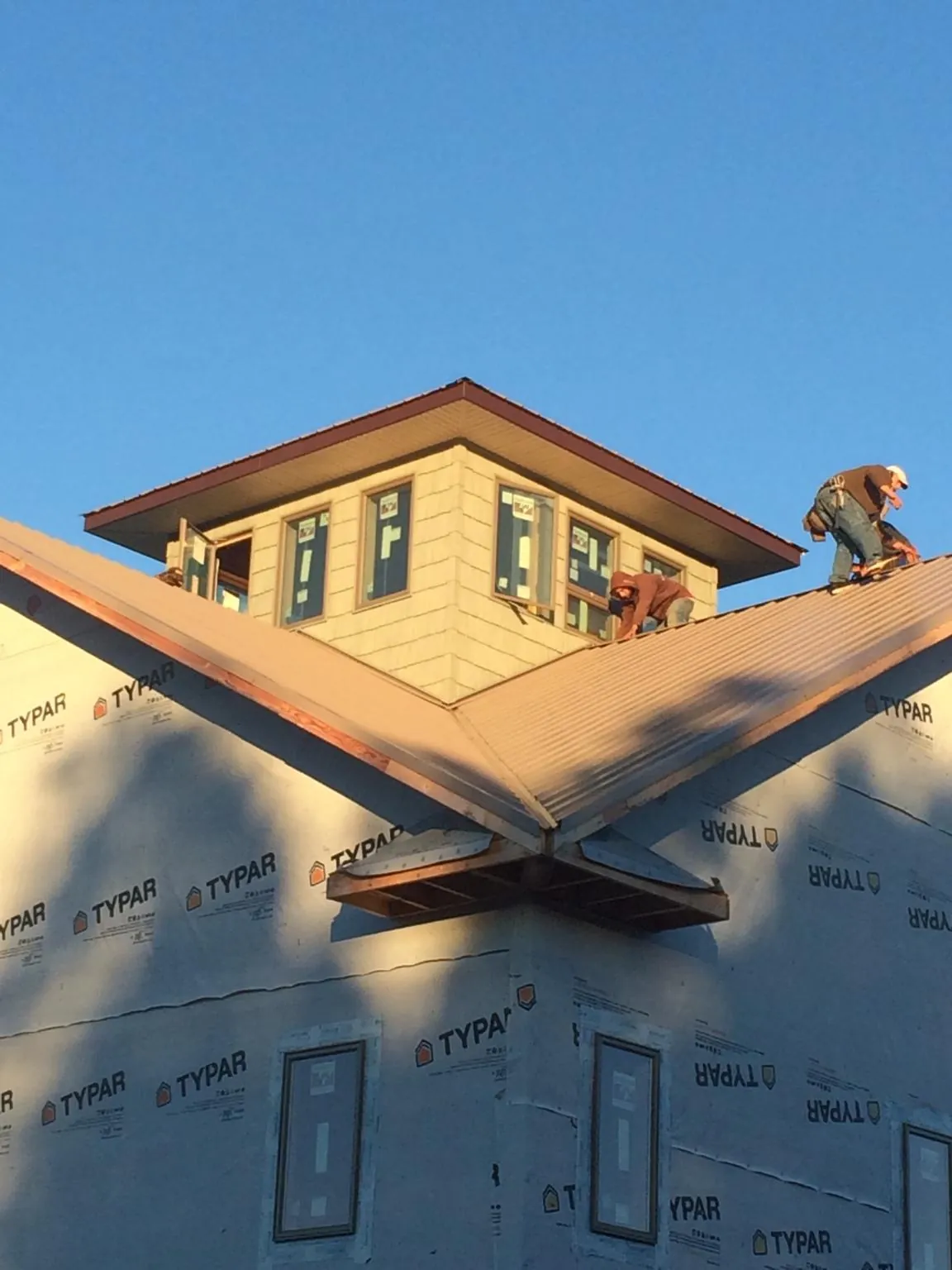 Roofers working around a rooftop cupola on a new metal roof at sunset — Roof Waterproofing in Saint Paul by Roofing Brothers
